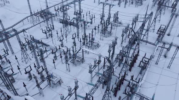 Aerial view of a high voltage electrical substation in cold snowy winter season.