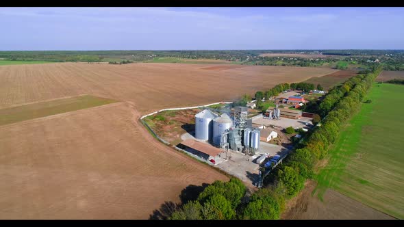 Storage silos on farm. Aerial view of grain silo in green field alt