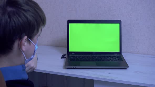 A Guy in a Protective Face Mask Communicates on a Video Conference and Gestures with His Hands alt