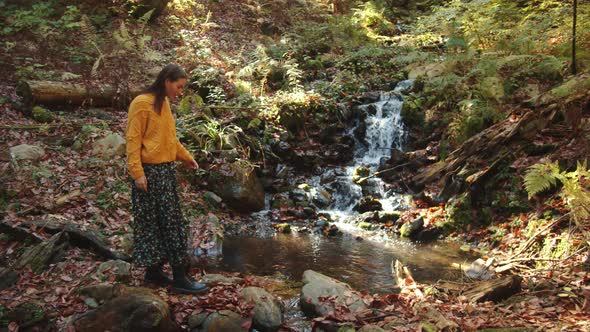 Young Girl is Carefully Stepping Over the Stones Nearby the Cascading Water Stream