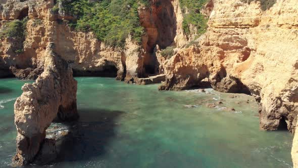 Rock formations in Rugged Algarve's southern cliffs encircled by emerald green sea, Portugal alt