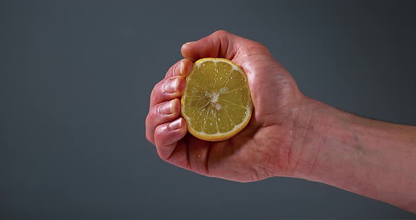Hand of Man Squeezing Lemon, citrus limonum against Black Background, Slow Motion 4K alt