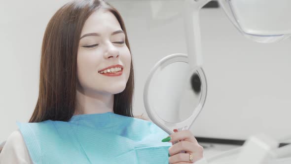 Beautiful Woman Examining Her Teeth in the Mirror at the Dental Clinic alt