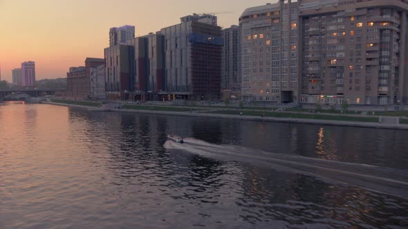 An Aerial View of a Boat That Floats on a River in the City Centre at Sunset