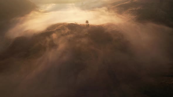 4K aerial view over a misty mountainous area. The great golden sun in the morning alt