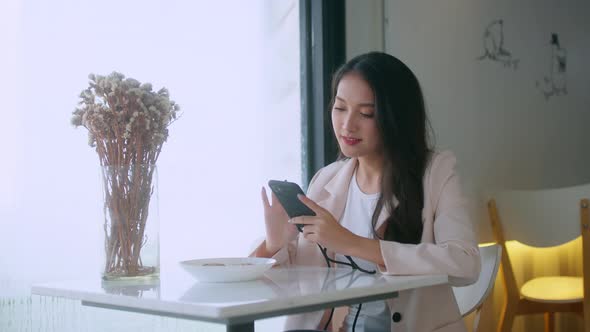 young attractive asian female wear casual cloth hand use smartphone and laptop device in cafe