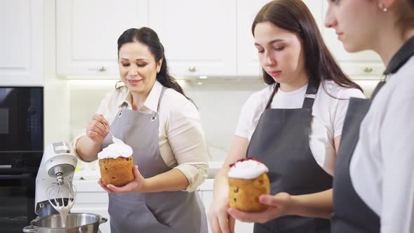 a Mother and Daughters Decorate Icing Dried Berries and Flowers Easter Cakes alt