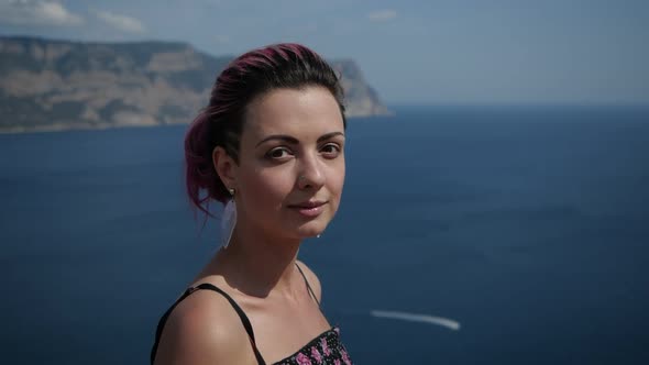 Girl with Purple Hair Smiles at the Camera Against the Backdrop of the Sea Bay
