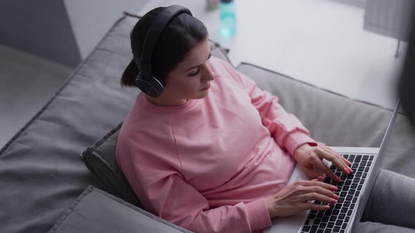 Relaxed Woman Working with Laptop Computer and Listening Music By Headphone alt