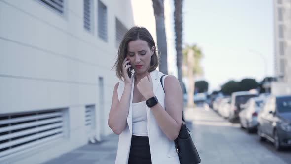 Young Fashionable Entrepreneur Talking on Phone and Looking at Smartwatch