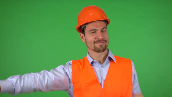 A Young Handsome Construction Worker Dances and Smiles at the Camera - Green Screen Studio alt