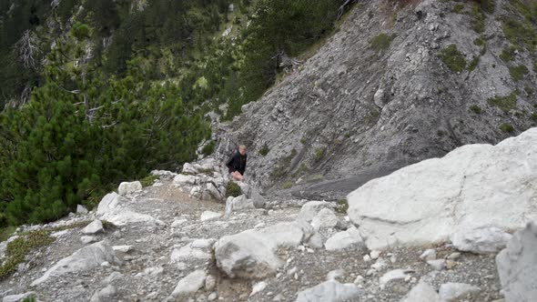 Man Hiker Tourist Going Up the Mountain on Sloping Rocky Slope Hiking Concept