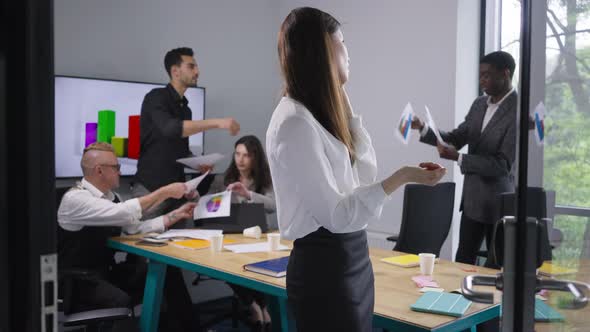Positive New Employee Talking on Phone Standing in Office with Multiethnic Colleagues Working at alt