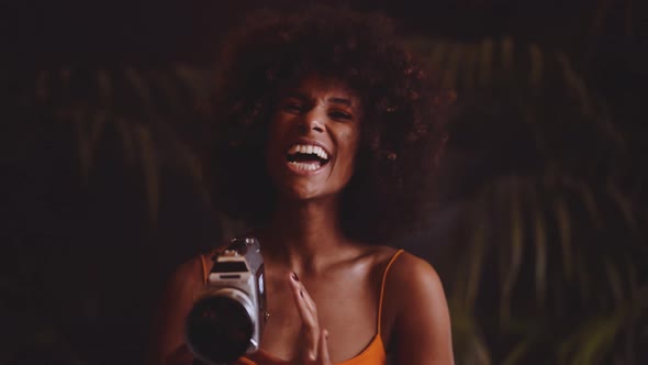 Woman With Afro Hair In Orange Dress Using Vintage 8Mm Camera alt