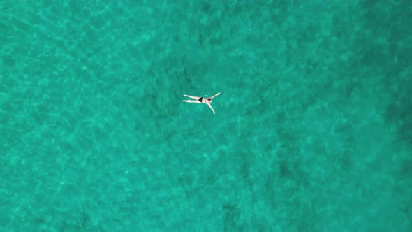Top Down Aerial View of Woman Swims on Crystal Clear Water in a Transparent Sea alt
