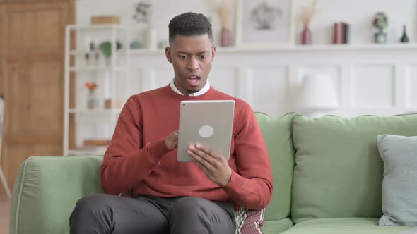 African Man having Loss on Tablet on Sofa alt