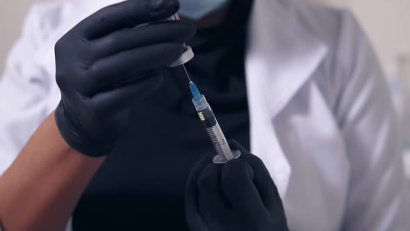 Closeup View of an Unrecognizable Professional Doctor in Black Gloves and Mask with Medical Syringe alt