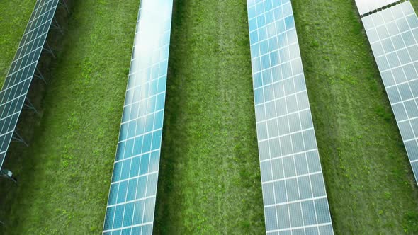 Flight Along Solar Panel on the Green Field. Solar Power Station for Production of Green Energy alt