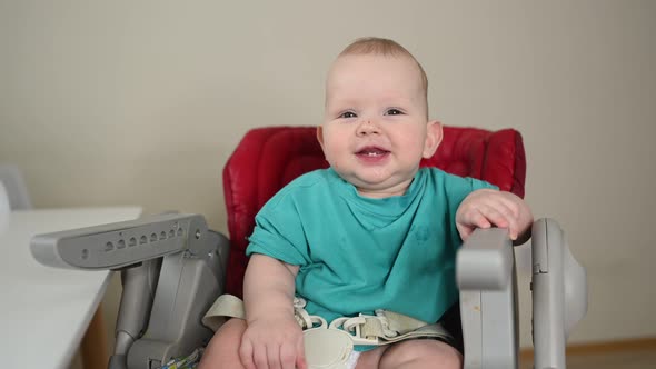 Little Emotional Newborn Funny Toddler Boy Sitting on Feeding High Chair