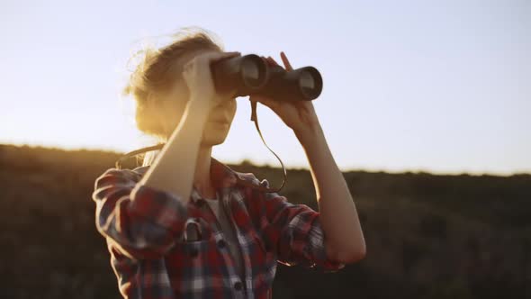 Blonde Caucasian Female in Plaid Red Shirt Using Binoculars to Look Forward in Slowmotion alt