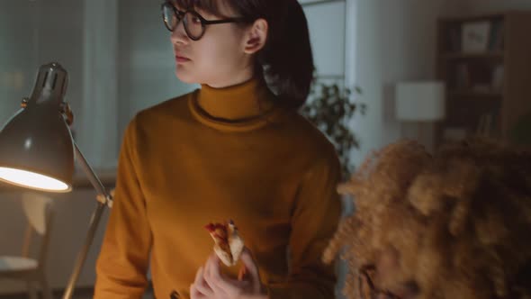 Diverse Coworkers Eating Pizza and Speaking in Office at Night alt