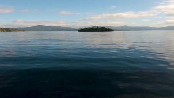 View from a boat on the driving towards a lone island in the center. Marlborough Sounds. Near Picton alt