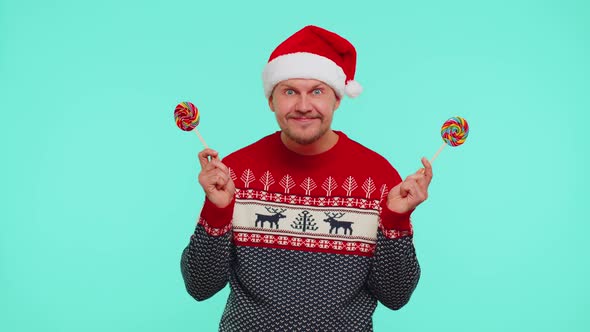Funny Man in Red New Year Sweater Holding Candy Striped Lollipops Hiding Behind Them Fooling Around alt