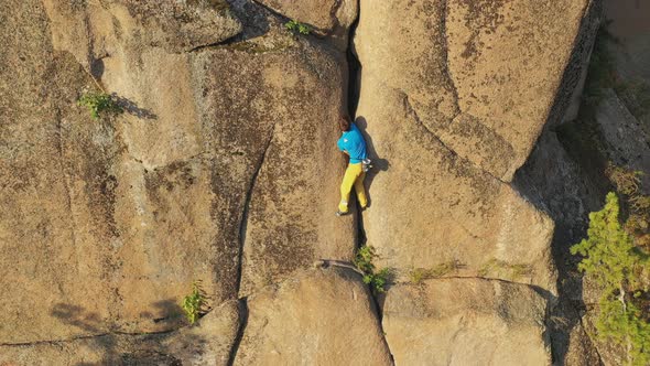 Aerial View of a Young Man Carefully Climbs a Rock Crack