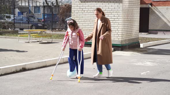 Mom Helps Daughter Learn To Walk On Crutches Stock Footage Videohive