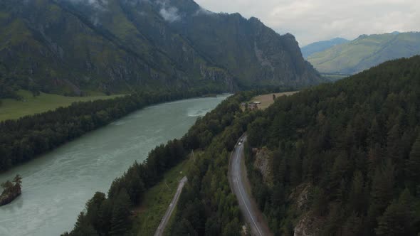 Katun river and traffic cars on road in mountains at during daytime