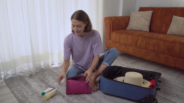 A Woman Packs Cosmetics in a Suitcase Preparing for a Trip to the Sea