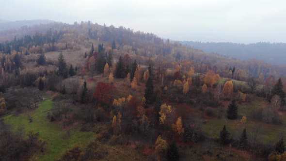 Aerial Drone Footage View: Flight over autumn mountain with forests and fields.