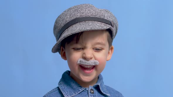 Child with a Gray Gray Mustache and a Hat Stands in the Studio alt