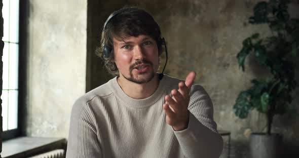 Happy Man in Headphones Looking at Camera Enjoying Video Meeting with Friends and Colleagues alt