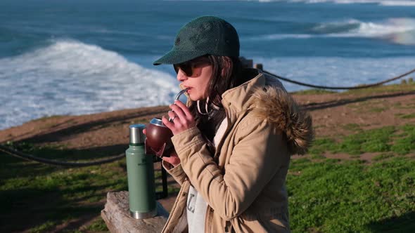 woman drinking mate, typical Argentine drink, on the beach, while watching the sunset pichilemu, pun alt