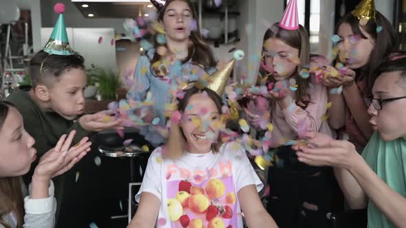 Teenagers throwing confetti at laughing girl at birthday party