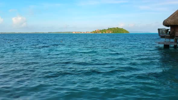 Overwater Dolly towards an Island with Overwater-Bungalow in the pacific ocean, Bora Bora, French Po alt