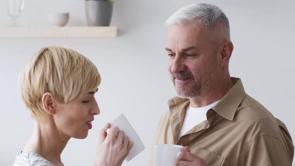 Portrait Of Cheerful MiddleAged Couple Enjoying Coffee In Kitchen alt
