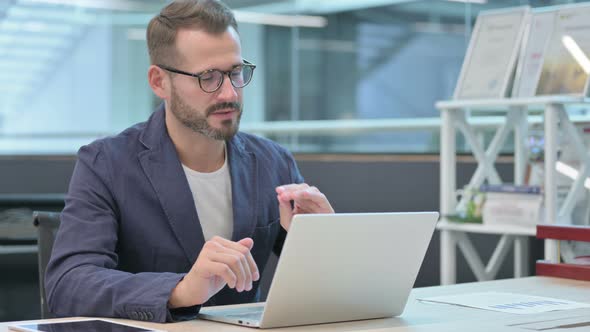 Middle Aged Businessman Talking on Video Call on Laptop in Office alt