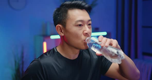 Asian Guy in Sportswear which Drinking Water During Exercising on Running Track alt