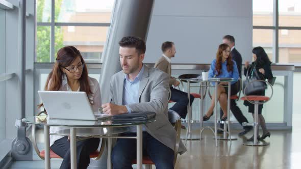 Businesspeople using laptop computer in office lobby