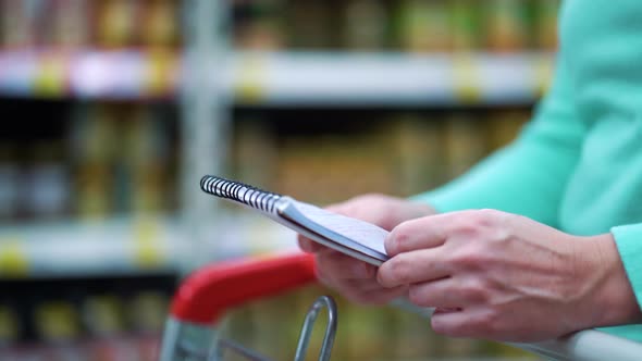 Female Hands Turning Page of Shopping List While in Supermarket alt