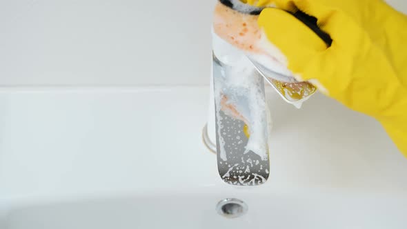 Top View of Woman in Ruber Gloves Washing and Cleaning Shiny Water Tap in Bathroom Sink