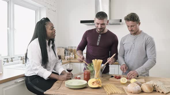 Gay male couple with African American woman friend talking in cooking party at home