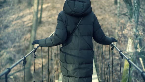 Woman Walking On Suspension Bridge. Tourist Walkway In Forest. Traveler Explore Forest.Wooden Bridge alt