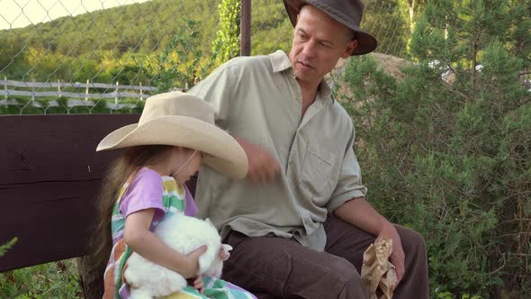 A Farming Family a Father and a Little Daughter with a Rabbit are Sitting Together on the Farm alt