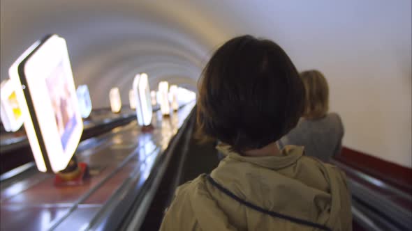 Girl Rides the Escalator in the Underground Subway Rear View