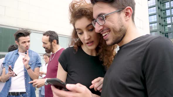 Group of friends using smartphone in city alt