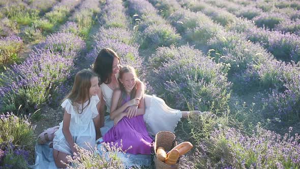 Family in Lavender Flowers Field at Sunset in White Dress and Hat