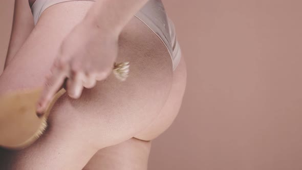 Young woman holding brush in her hand anti-cellulite treatment. Cellulite problem. alt